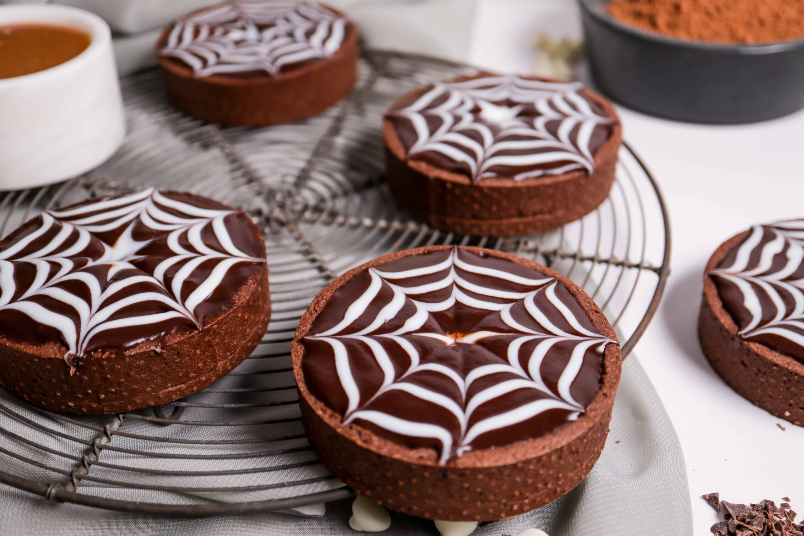 side view of chocolate tarts with white spider web design on top