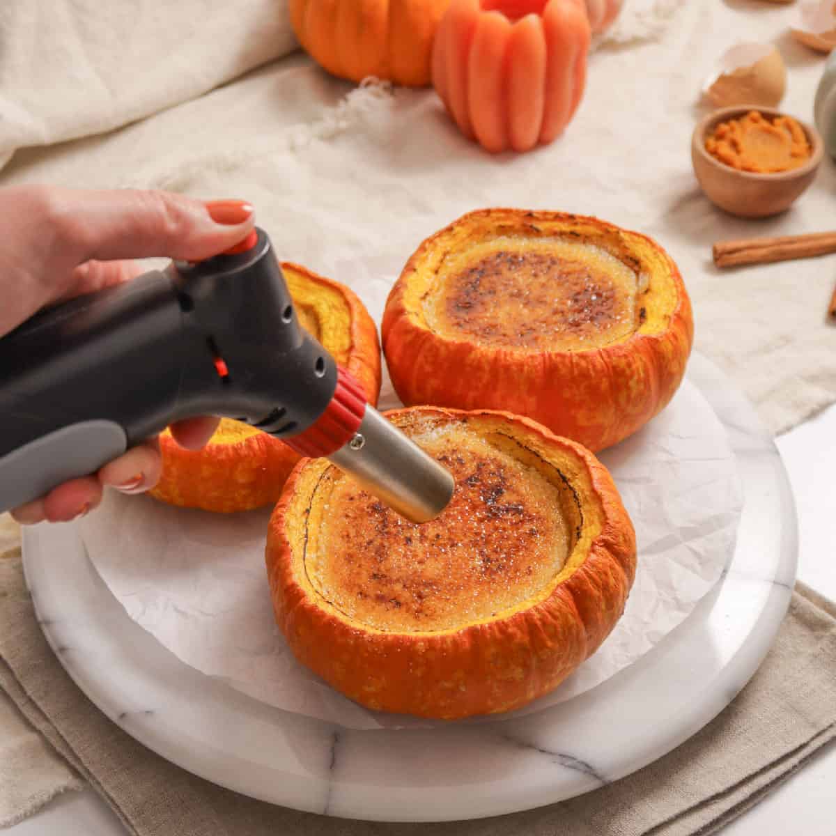 torching the tops of pumpkin spice creme brulee