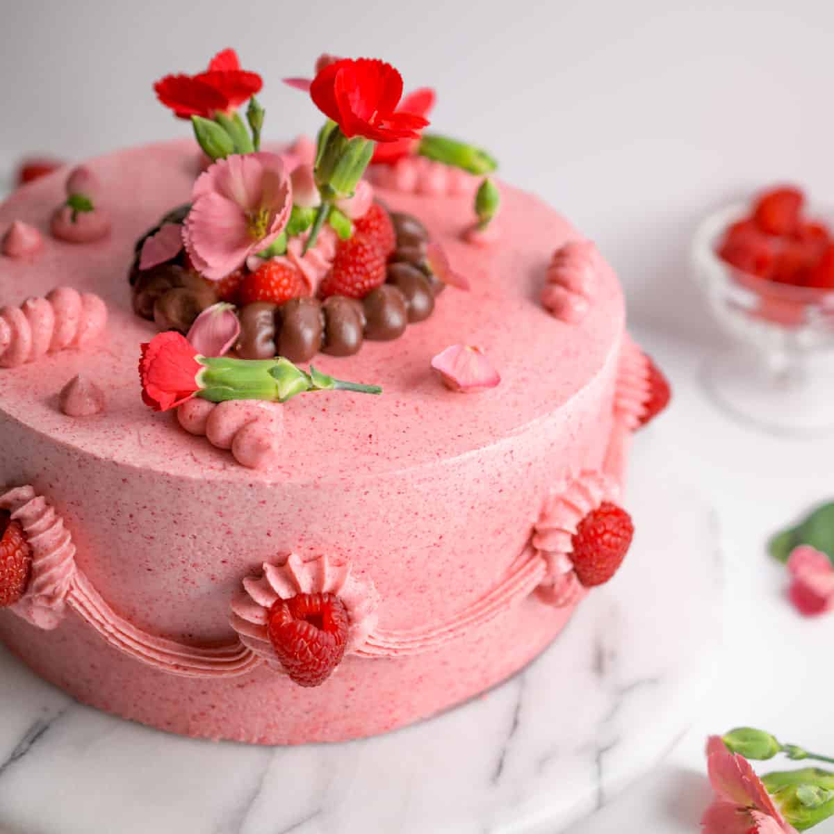 raspberry chocolate layer cake, round two layer pink cake, flowers, ganache and raspberries on outside