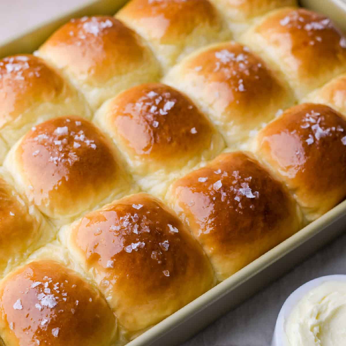 potato rolls recipe with instant potatoes rolls in a pan with melted butter and flaky salt