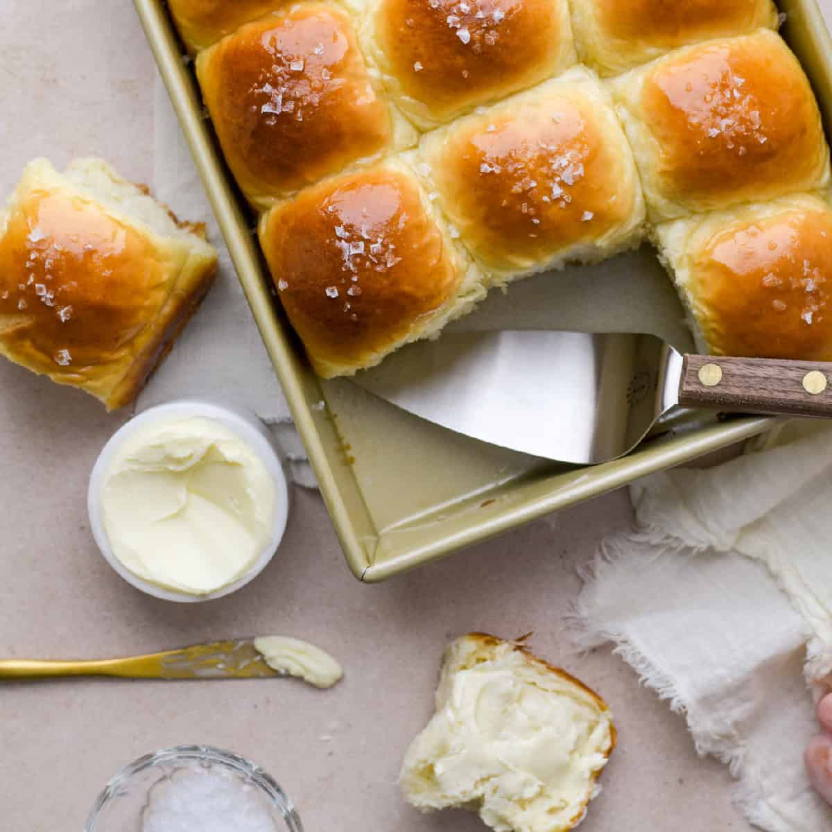 overhead view of potato rolls recipe with instant potatoes rolls in a pan with melted butter and flaky salt
