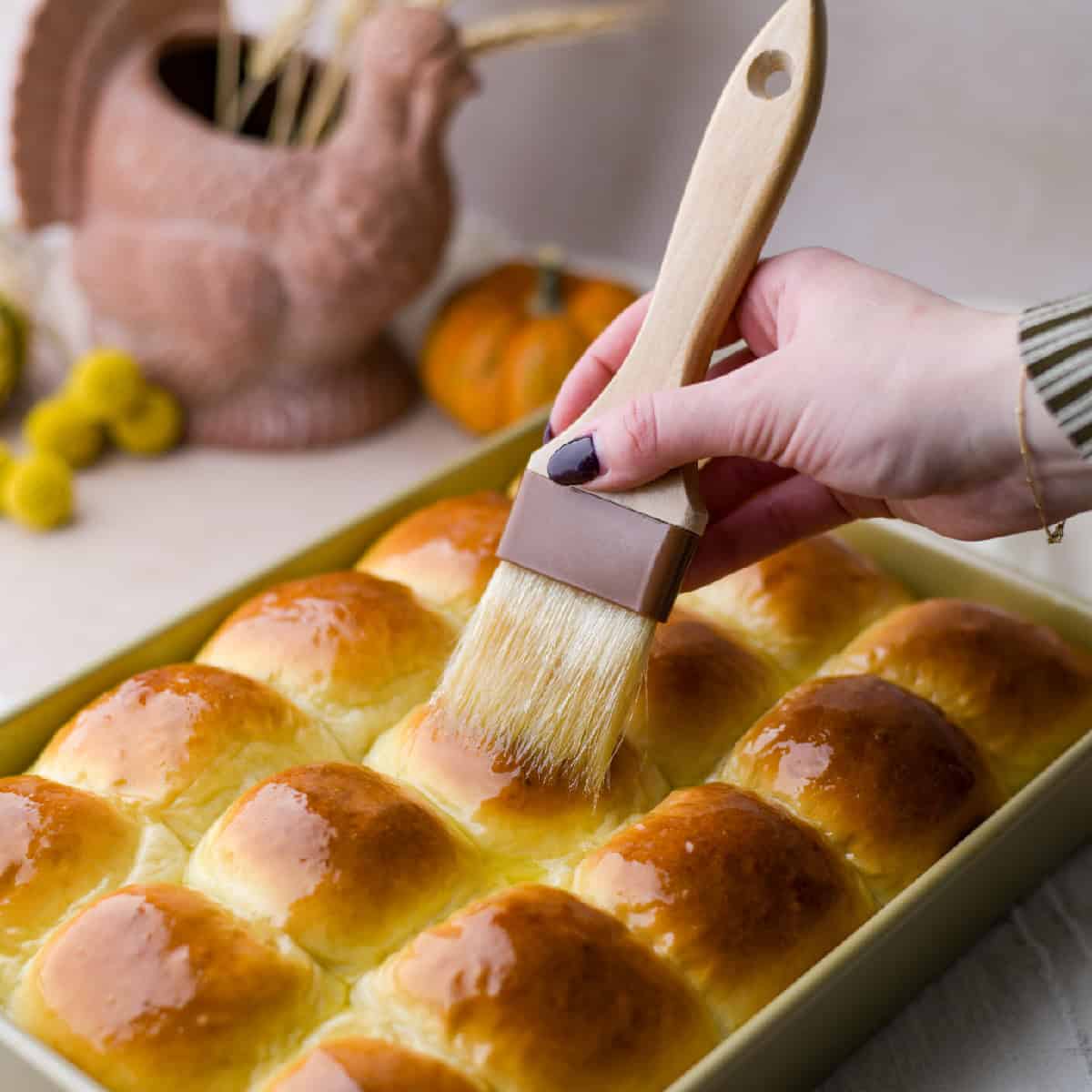 baked potato rolls in a pan being brushed with melted butter