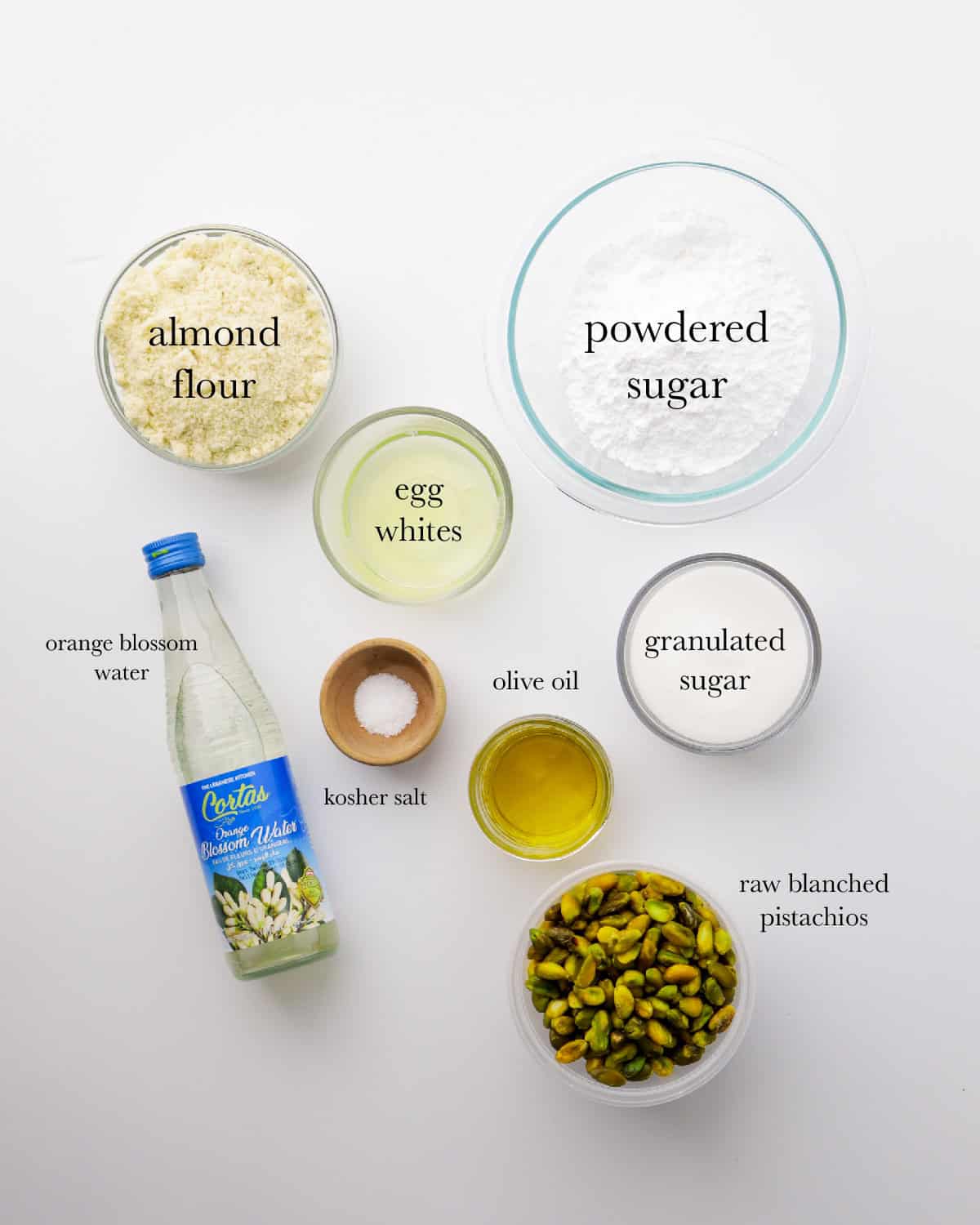 pistachio macaron ingredients, top to bottom: almond flour, powdered sugar, egg whites, orange blossom water, kosher salt, olive oil, granulated sugar, raw blanced pistachios.