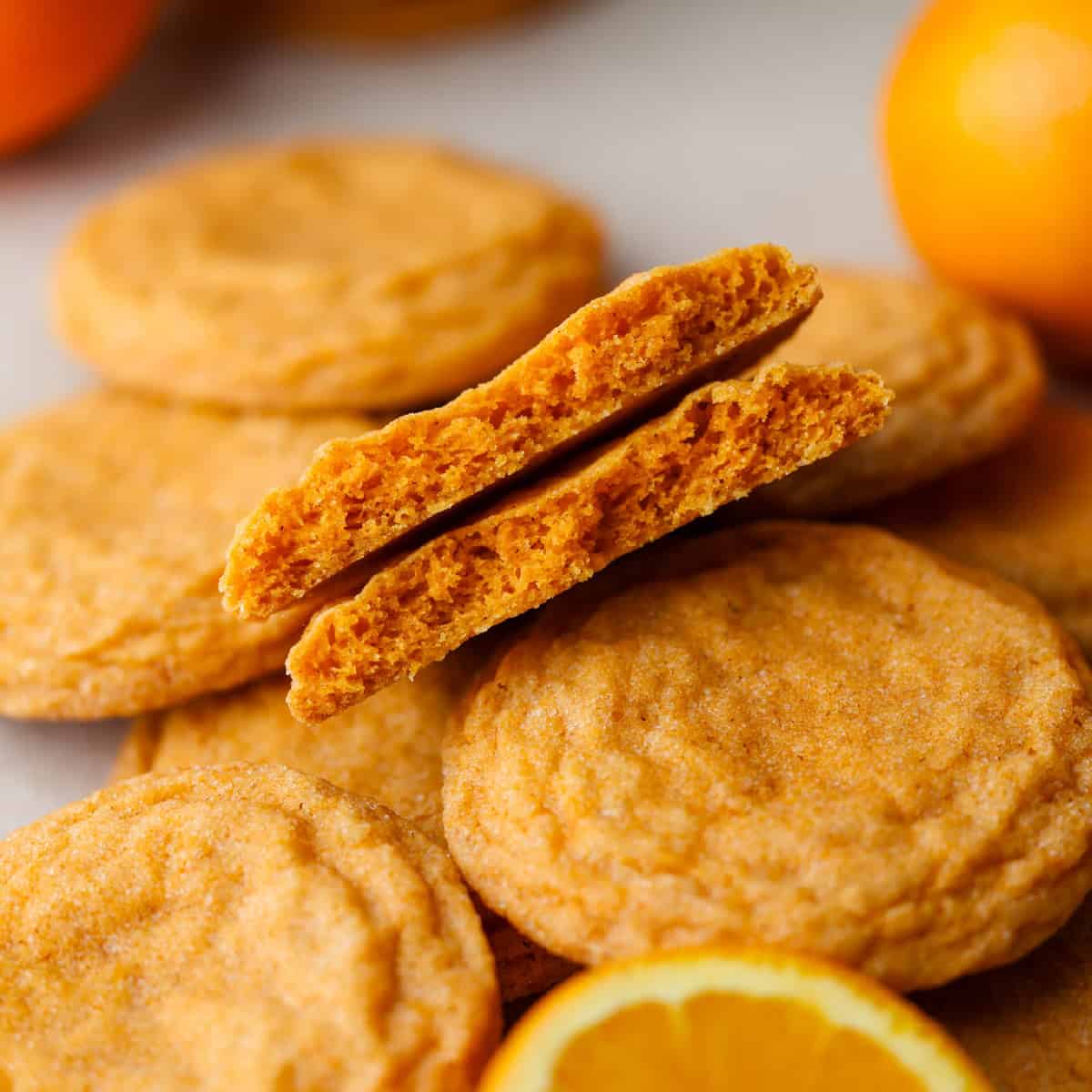 cookie broken in half atop pile of orange cookies.